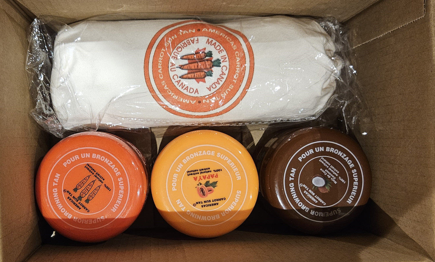 Three containers and a wrapped item in a cardboard box with visible branding.